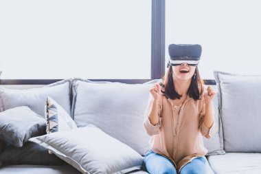 Oturma odasında Vr kulaklık giyen eğlenceli ve heyecanlı kadın görüntüsünü