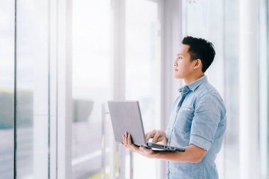 Ofis Binası parlak geleceği için olumlu duygu ile dizüstü bilgisayar kullanan emin Asya adam. iş başarı kavramı.