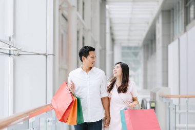 Renkli alışveriş torbaları tutarak ve alışveriş, alışveriş merkezinde birlikte eğleniyor zevk mutlu Asya çift. Tüketim, aşk, flört, yaşam kavramı