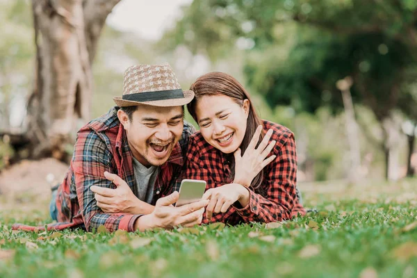 Glückliches und lächelndes Paar schaut aufs Smartphone — Stockfoto