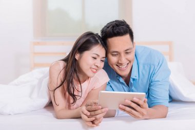 Asya çift yatağa dijital tablet kullanma