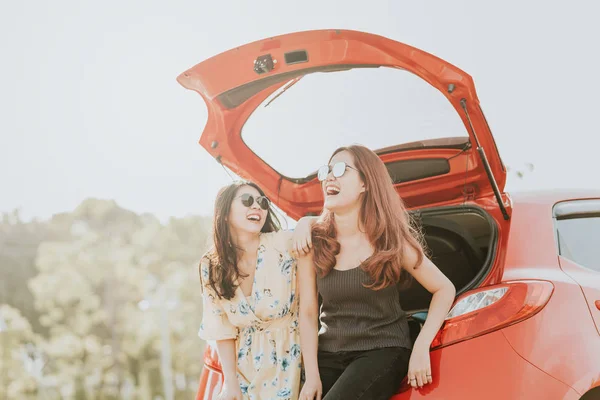 Счастливая азиатская девушка лучшие друзья сидя автомобиль багажник — стоковое фото
