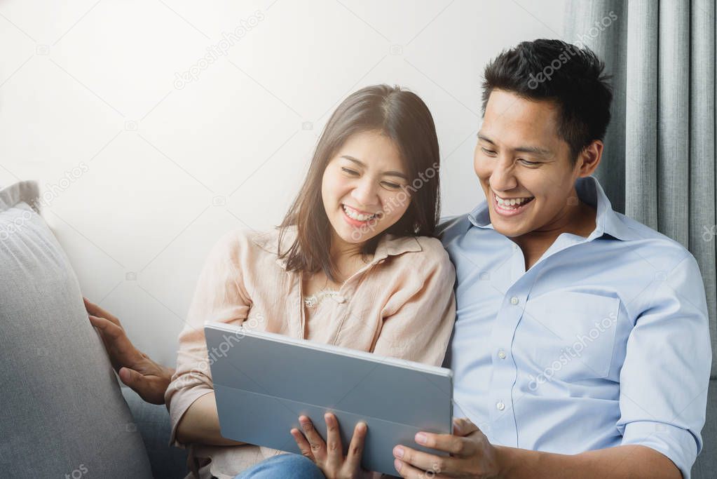 Asian couple smiling while using digital tablet