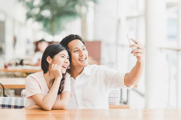 Selfie モダンな建物で屋内にスマート フォンを使用して幸せなアジア カップル — ストック写真