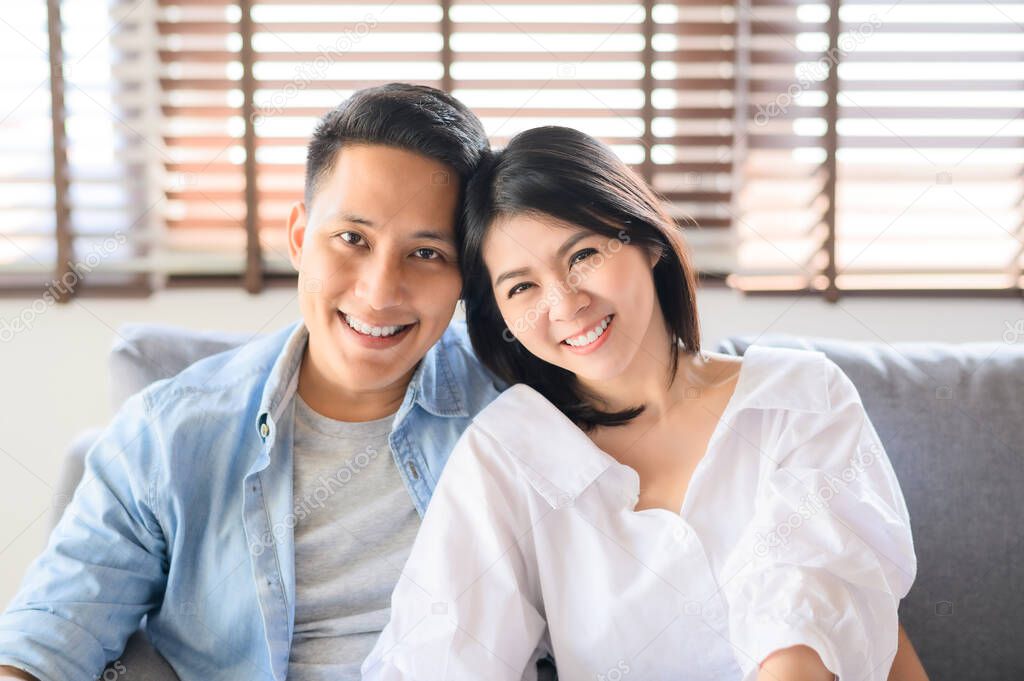Asian couple in love smiling relaxing on sofa at home
