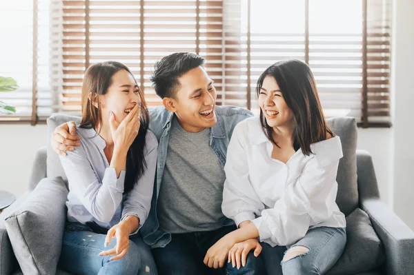 Happy three asian friends itting on sofa laugh and having fun