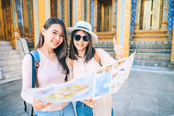 Mulheres asiáticas dando polegares para cima mão sinal viagem no templo da esmeralda buddha, Tailândia — Fotografia de Stock