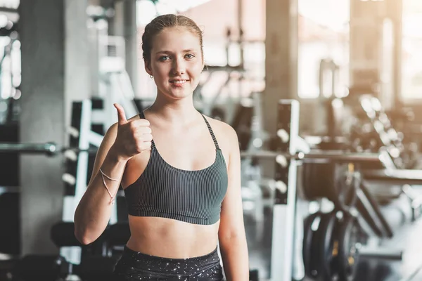 Mujer sana mostrando el pulgar hacia arriba signo en el gimnasio de fitness — Foto de Stock