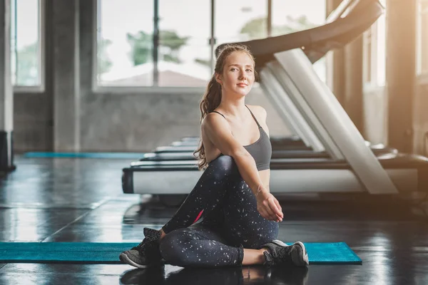 Happy young caucasian woman stretching in gym — Stock Photo, Image
