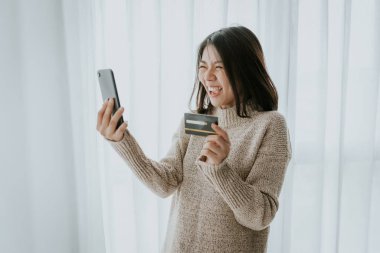 Happy Asian woman using credit card for online shopping with sma