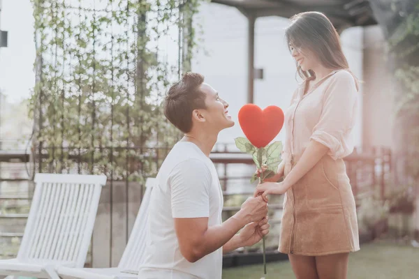 Asiatico uomo su dare cuore forma fiore a suo fidanzata . — Foto Stock