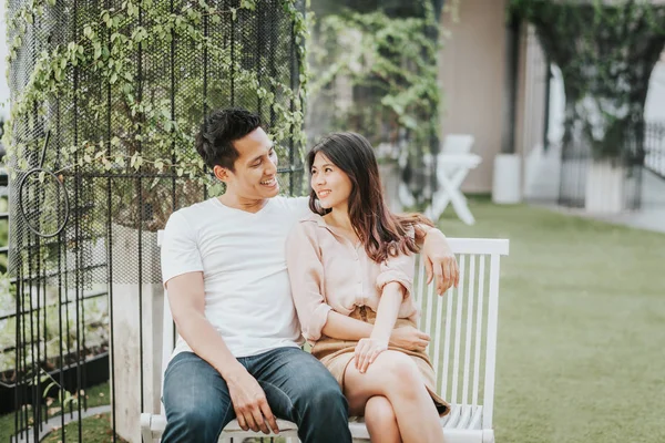 Pasangan Asia yang bahagia tersenyum sambil duduk di bangku cadangan — Stok Foto