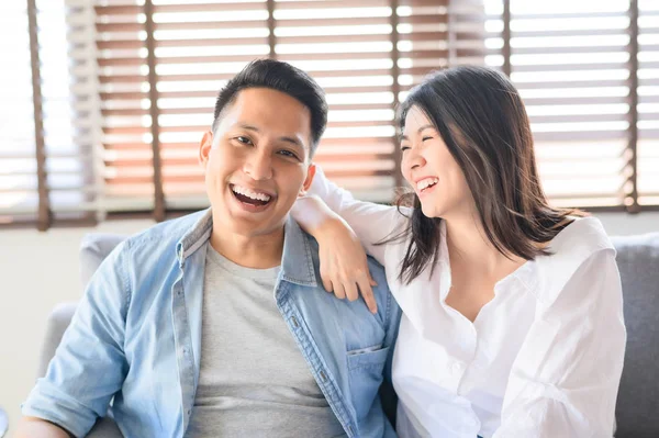 Asian couple in love smiling and laughing on sofa at home — Stockfoto