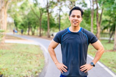 Parkta koşmayı bitirdikten sonra mutlu Asyalı terli koşucunun portresi.