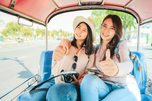 在泰国曼谷度假期间 两名快乐的亚洲女孩最好的朋友坐在塔克出租车里 手举大拇指 享受愉快的公路旅行 — 图库照片