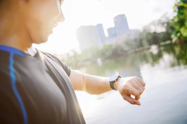 Healthy sport man runner checking his heart rate after running from smart watch on wrist in city park in the morning