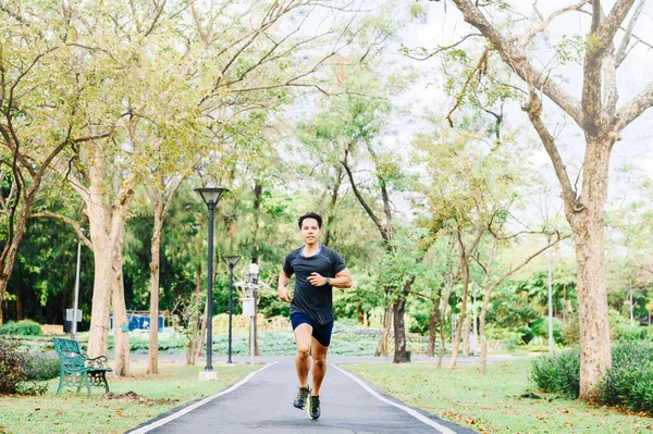 幸せなアジア人男性が朝公園で屋外を走っています — ストック写真