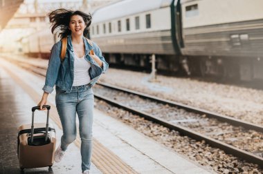 Tren istasyonunda bavulla koşan Asyalı kadın turist. Etkin ve seyahat yaşam tarzı konsepti