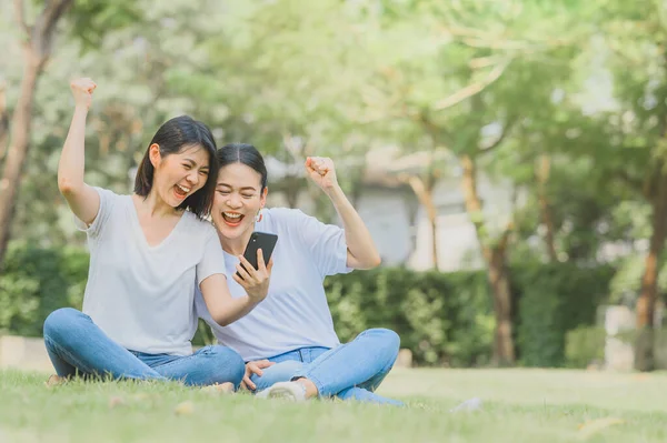 Glada Asiatiska Kvinnor Bästa Vänner Firar Framgång Håller Mobiltelefon Sitter — Stockfoto