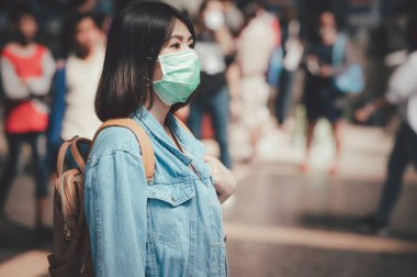 Koronavirüs gribi virüsünden ve kamusal alandaki hastalıklardan korunmak için Asya 'lı kadın turist maskesi takıyor.