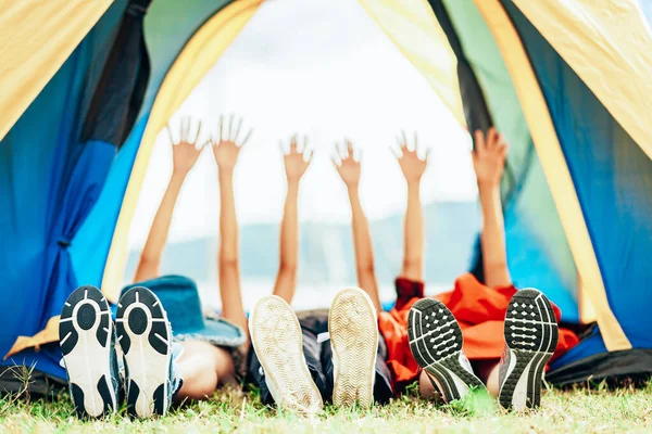 A group of happy friends sleep and raised their hands in a tent while camping travel during the holidays. Travel camping outdoor concept.