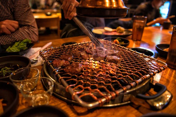 Kuchař vaření Bbq hovězí maso v ohni na hosty stůl v restauraci — Stock fotografie