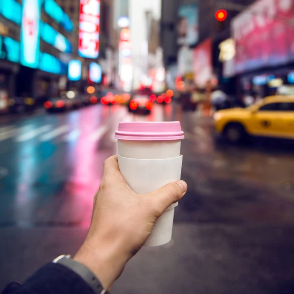 Kawa na wynos w mieście. Ręka trzyma kubek papierowy biały kawy w mieście ulicy w godzinach porannych. — Zdjęcie stockowe