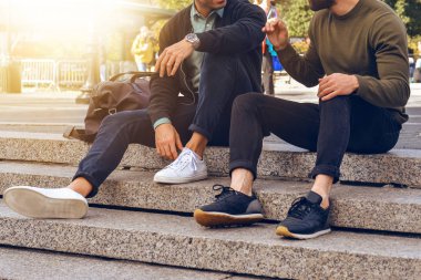 Yaşam tarzı fotoğraf adımları sokak ve konuşan rahat sokak tarzı giyim ve spor ayakkabılar giyiyor şehirde oturan iki erkek arkadaş.