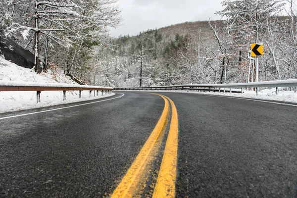 Beautiful winter landscape with highway road with turn and snow-covered trees. Clean mountain asphalt winter road with yellow marking double lines and sign — Stock Photo, Image