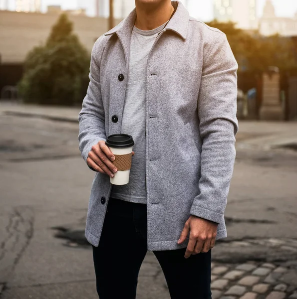 Man bedrijf koffie cup dragen fluweel grijze jas en staande op stad straat op de weg naar het kantoor — Stockfoto