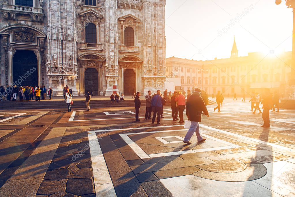 crowd of tourist people walking in center of old town near Duomo in Milan, Italy at sunset time