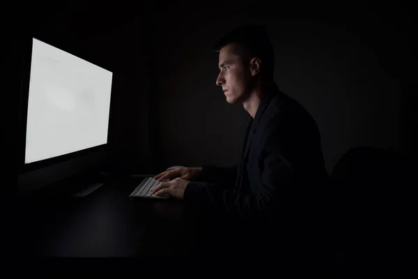 Látszó-hoz idegen rádióadást figyel képernyő és gépelés-ra billentyűzet számítógép közben a éjszakai munka az irodában dolgozó férfi. — Stock Fotó