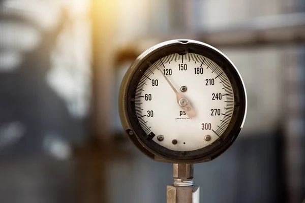 Nahaufnahme eines industriellen Manometers, das den Gasdruck auf der Anlage misst. Stromerzeugungsrohre und Ventile auf dem verschwommenen Hintergrund. — Stockfoto