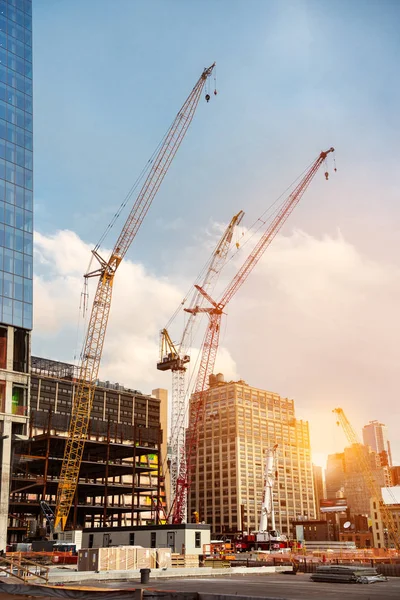 Construction cranes on construction site build office skyscraper building in New York City at sunset time. — Stock Photo, Image