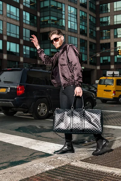 Uomo turistico alla moda con una borsa che prende il taxi su New York City street — Foto Stock