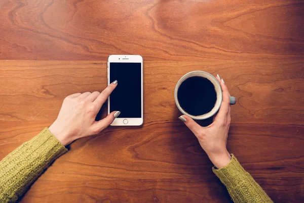 Frau trinkt Kaffee und berührt Telefonbildschirm mit dem Finger. — Stockfoto