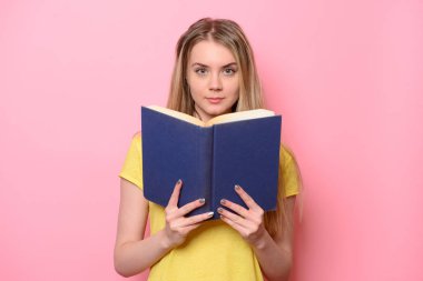 Güzel sevimli kadın, pembe arka plan izole kitap okuma