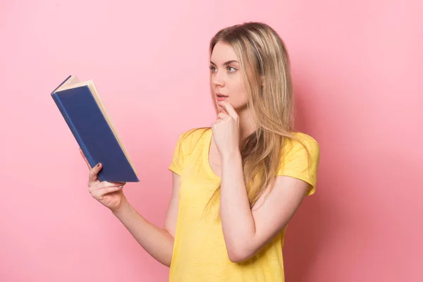 Mädchen liest ein Buch und denkt nahe rosa Wand — Stockfoto