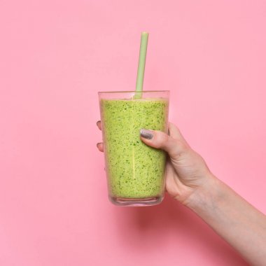 Smoothie shake pembe duvara tutan kadın el. İçme yeşil sağlıklı güler yüzlü kavramı