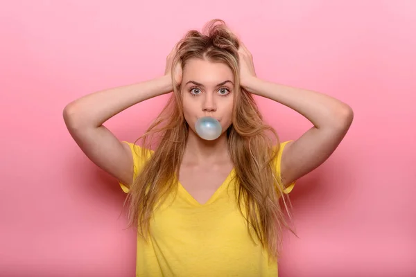 Carino donna che soffia gomma da masticare blu vicino al muro rosa — Foto Stock