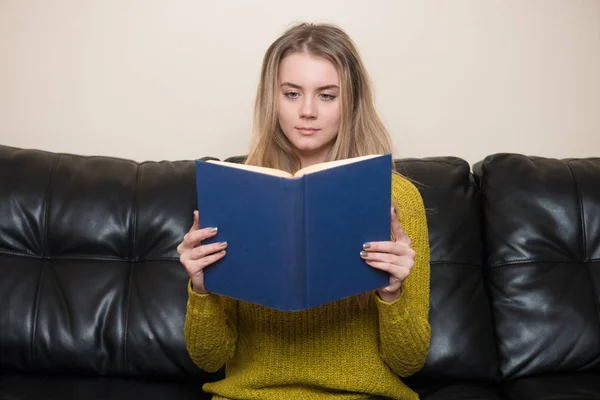 Frau liest ein Buch zu Hause auf dem Sofa — Stockfoto
