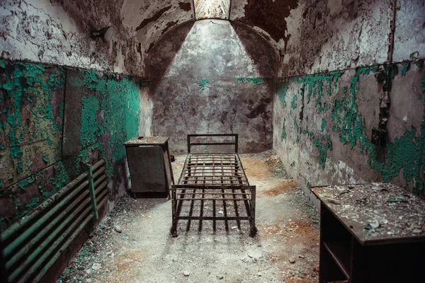 Sala de celas abandonada com estrutura de cama enferrujada velha e parede de peeling — Fotografia de Stock