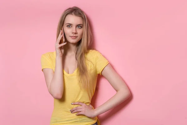 휴대 전화 서 분홍색 벽 근처에 아름 다운 젊은 성인 여자 — 스톡 사진