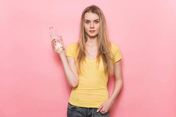 Mulher bonita com corpo perfeito segurando garrafa de água de plástico em pé perto da parede . — Fotografia de Stock