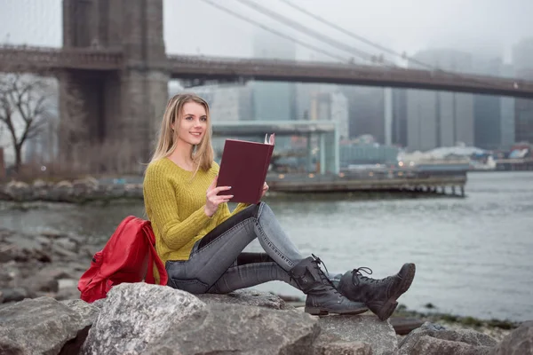 Fiatal gyönyörű diák lány olvasó egy könyv ül New York városára. Tanulmány az USA-ban egyetemi koncepció. — Stock Fotó