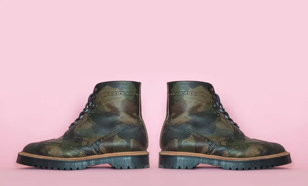 Vojenské kožené boty na růžovém pozadí. Koncept války a kus. — Stock fotografie