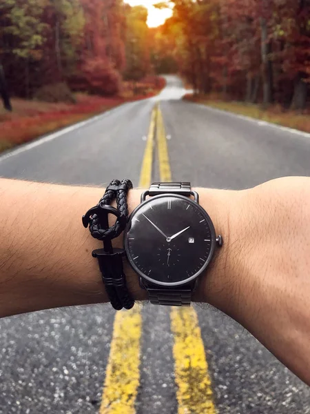 Hombre comprobar el tiempo en el reloj con estilo en la carretera forestal escénica. Accesorios hombre reloj y pulsera concepto . —  Fotos de Stock