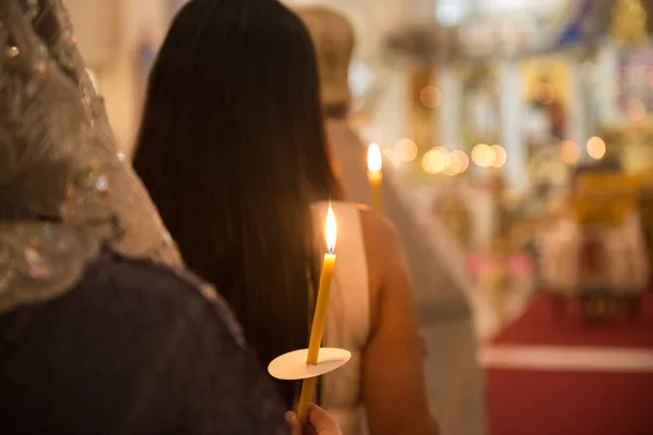 Persone che pregano in chiesa con le candele in mano — Foto Stock