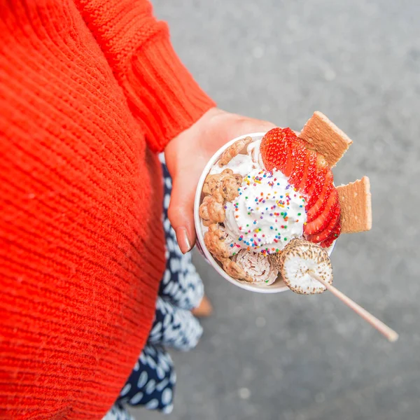 Girl holding colorful handmade ice cream cup with strawberry and marshmallows outdoors — Stock Photo, Image