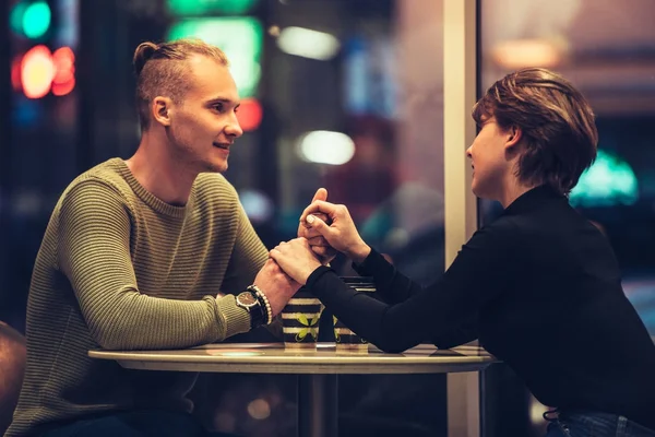 Jong volwassen koppel met een datum in café en drinken koffie hand in hand — Stockfoto